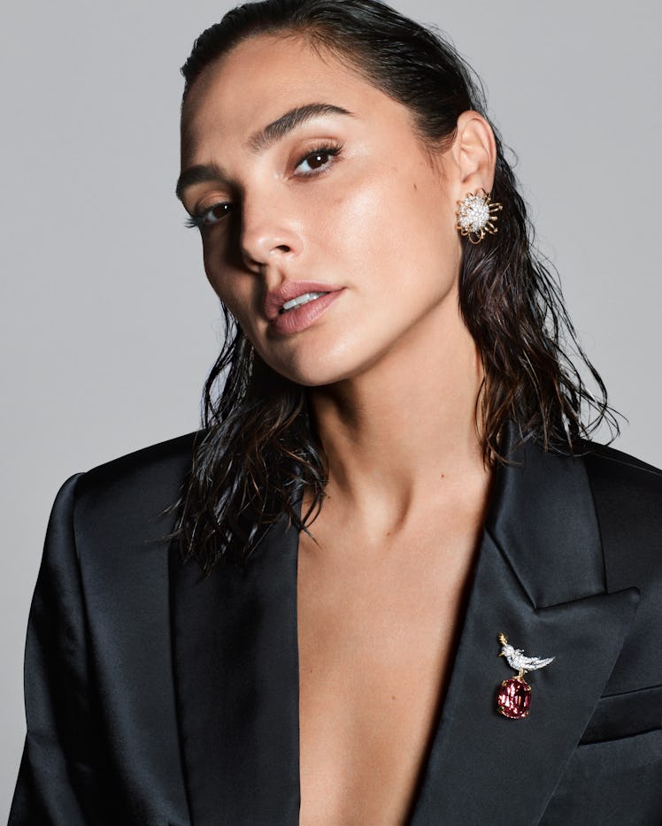 Gal Gadot in a black blazer wearing a brooch and earrings
