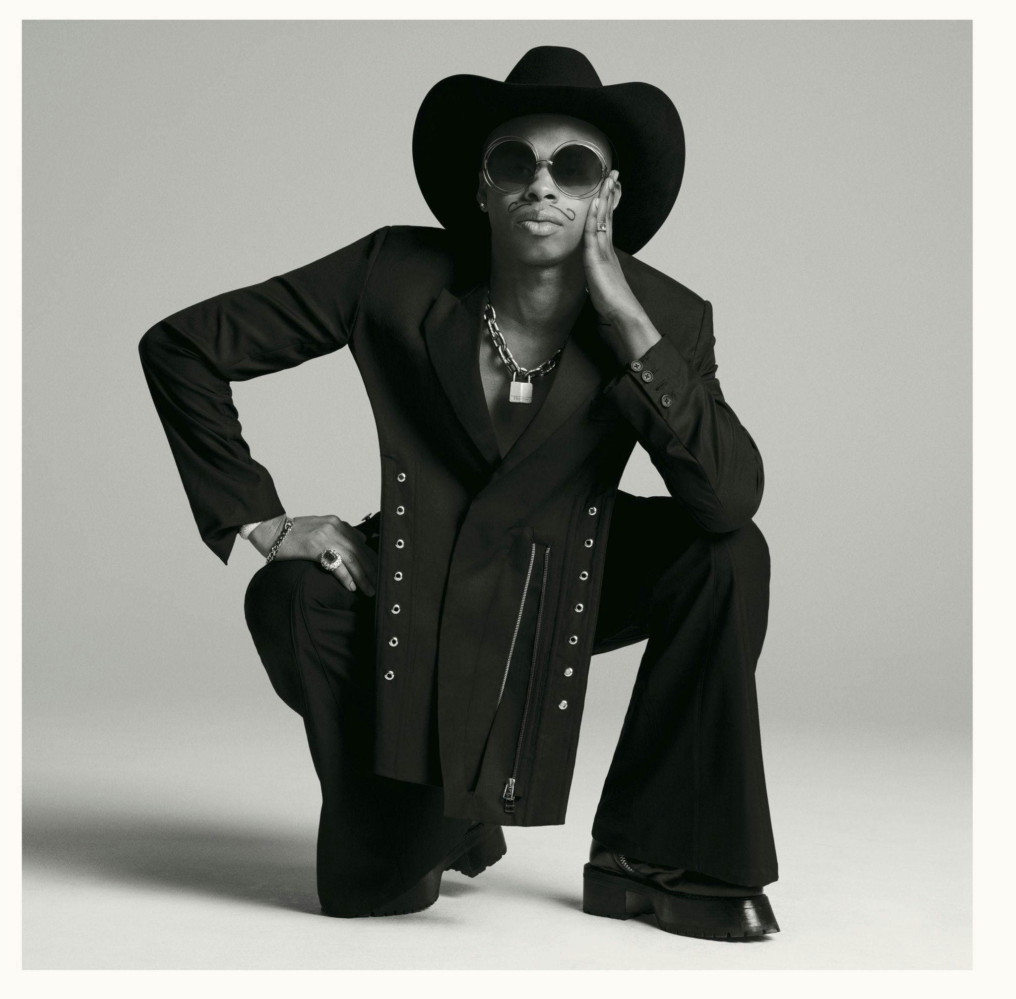 Shayne Oliver crouching down and wearing a hat and sunglasses