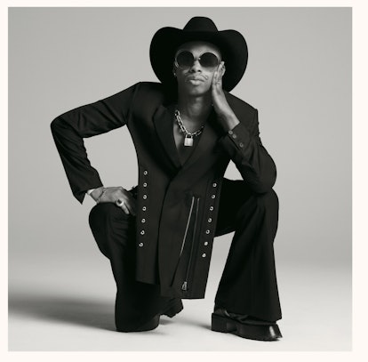 Shayne Oliver crouching down and wearing a hat and sunglasses