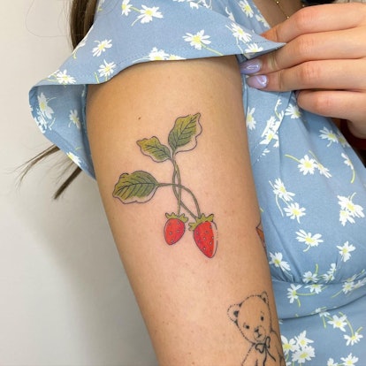woman's arm with a colorful strawberry tattoo