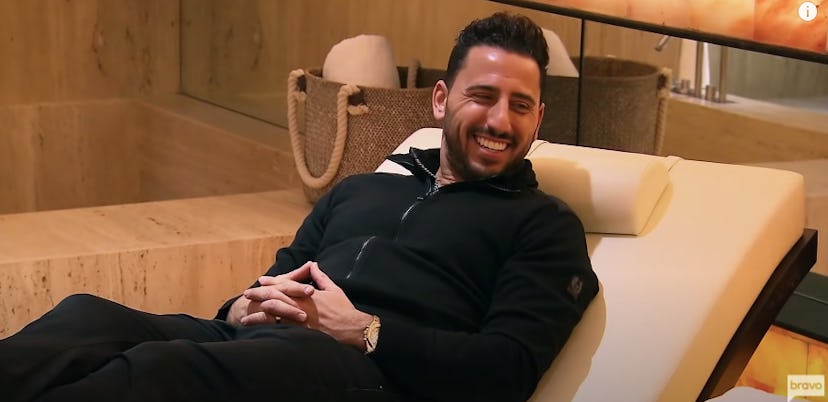 TV personality and realtor Josh Altman sits on a couch in a house he's showing. 