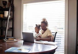 woman working in home office with child on her lap, everyday is take your child to work day