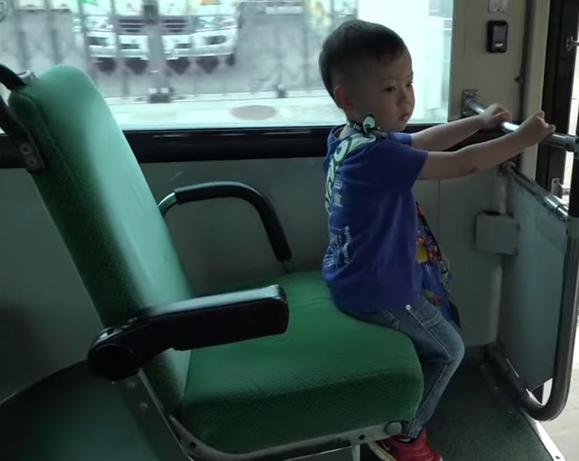 A toddler from 'Old Enough' sits on a city bus.
