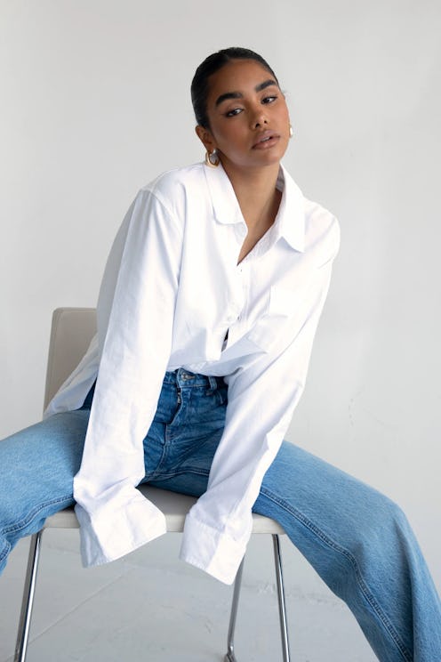 a model wearing a white oversize button-down shirt with jeans