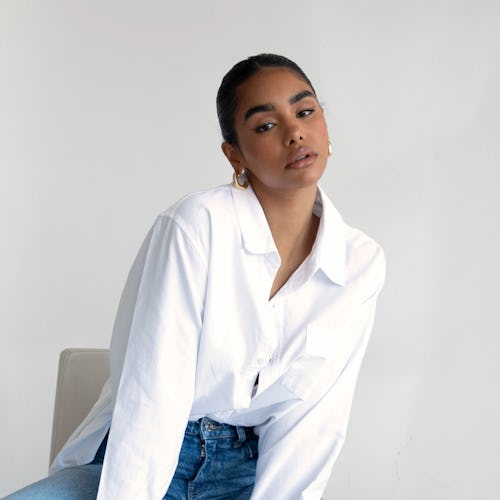 a model wearing a white oversize button-down shirt with jeans