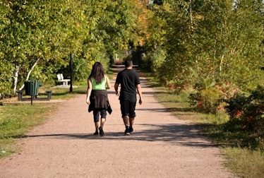 Young adult man and woman go for a brisk walk in the park on a sunny day.