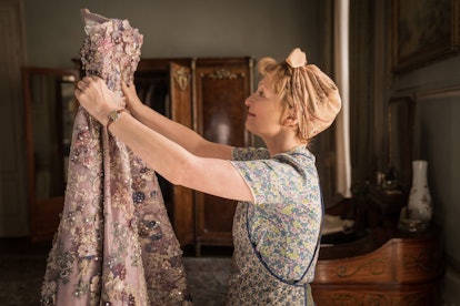 Lesley Manville holding up a Dior couture gown in 'Mrs. Harris Goes to Paris'