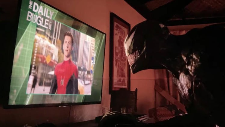 Venom looking at a TV display that shows Tom Holland as Spider-man