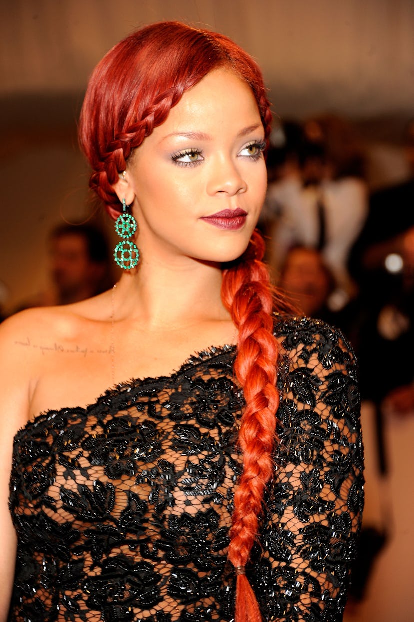 Rihanna with red hair tied into a braid at the 2011 Met Gala.