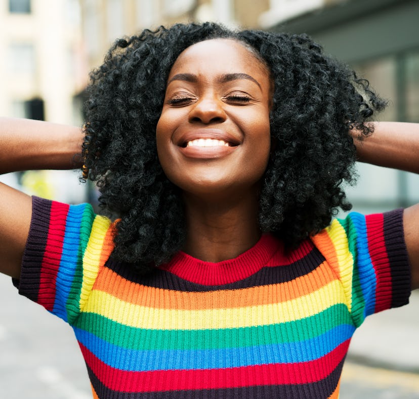 Happy young woman smiling over her shiny and defined curls after co-washing her curly hair.