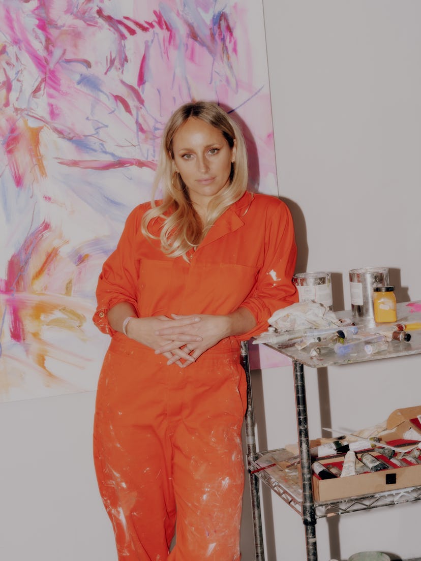 Kylie Manning standing by one of her paintings and materials