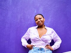 Young woman smiling against a purple background on the best day in May 2022 for every zodiac sign.