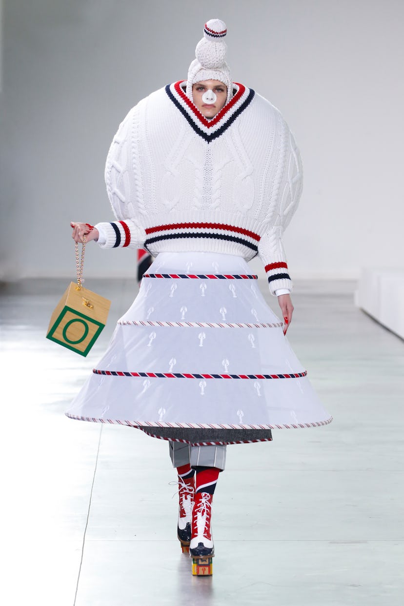 A female model walking in a snowball white gown by Thom Browne