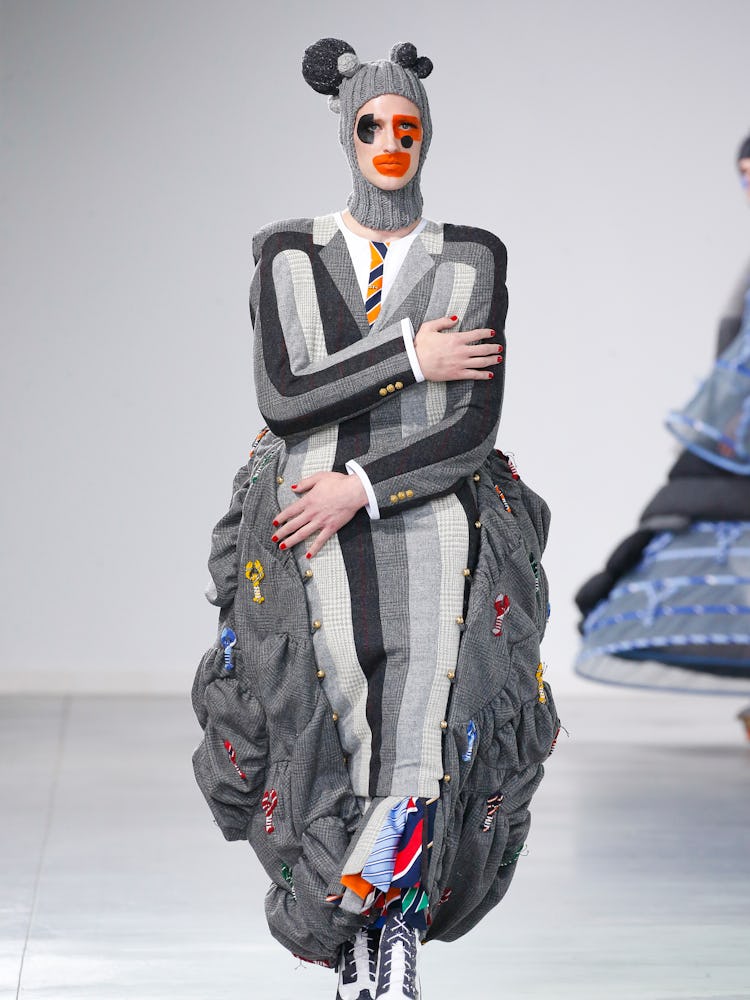 A model walking in a grey striped jacket and headpiece with ears for Thom Browne Fall 2022
