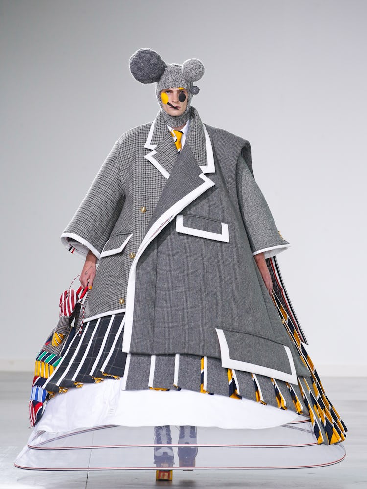 A model walking in a grey gown and teddy bear ears by Thom Browne