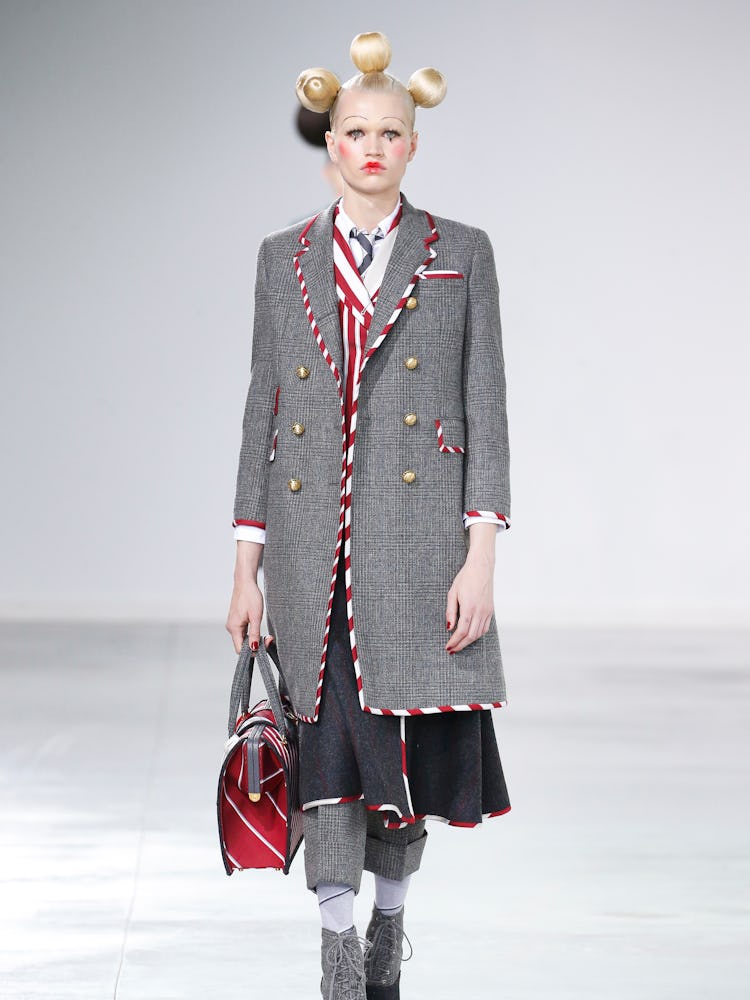 A model walking the runway in a long grey blazer and dark blue skirt for Thom Browne Fall 2022 