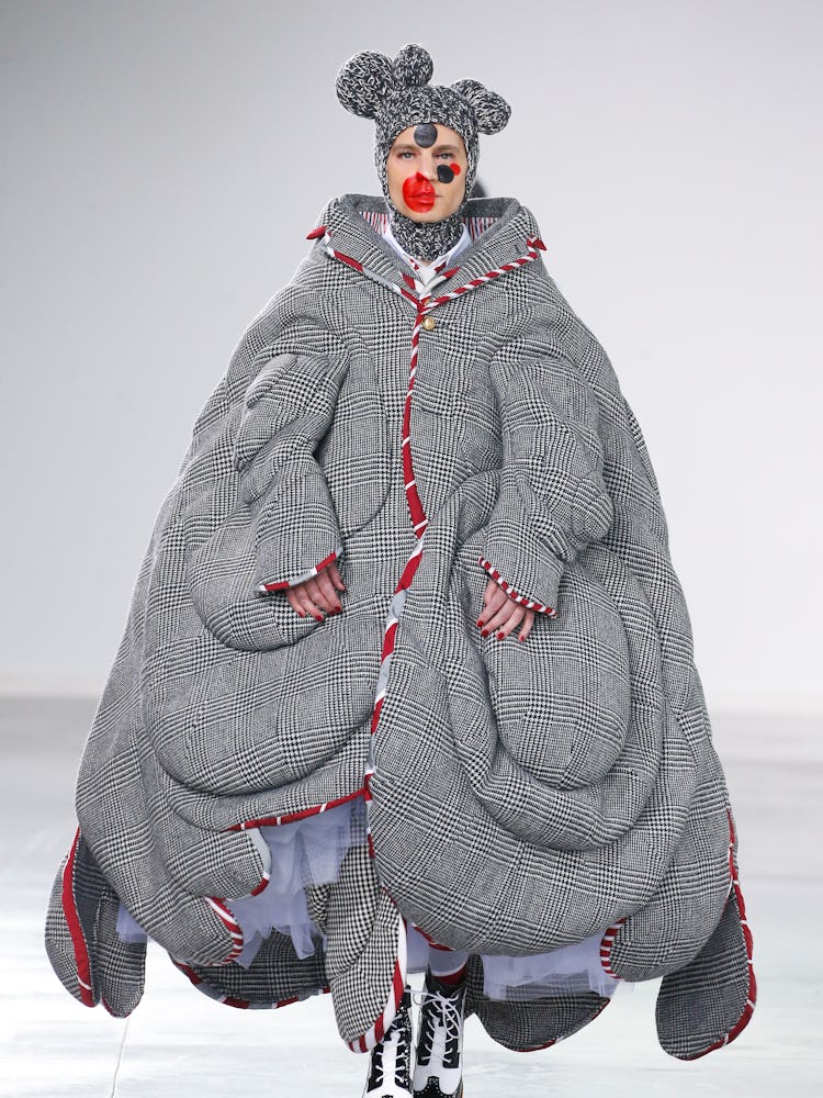 A model walking in an oversized grey coat and headpiece with teddy ears by Thom Browne 