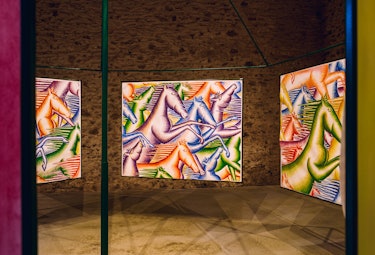 three colorful paintings of horses hanging in a barn exhibition space