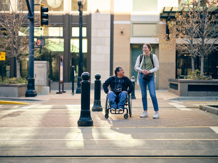 A man in a wheelchair and female friend on the sidewalk