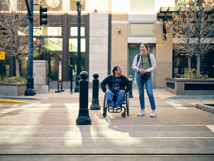 A man in a wheelchair and female friend on the sidewalk