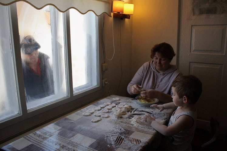 Baking with Grandmother, while Grandfather looks in the window, Ukraine.