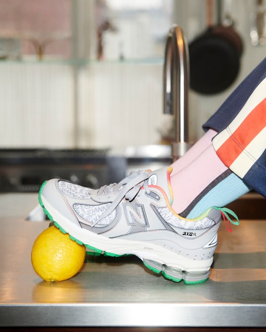 The model wearing Ganni And New Balance's Y2K Sneakers leans feet on a lemon.