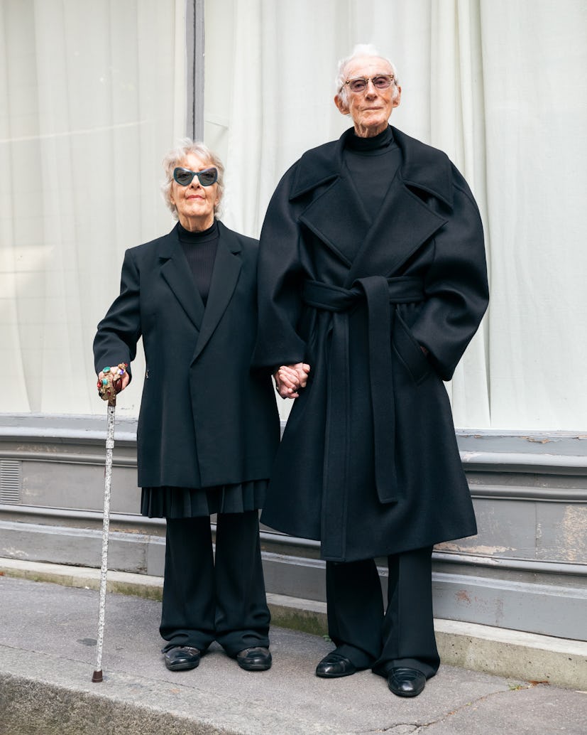 an elderly woman and man wearing sharp black outfits