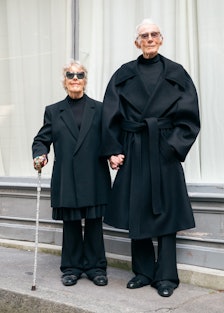 an elderly woman and man wearing sharp black outfits