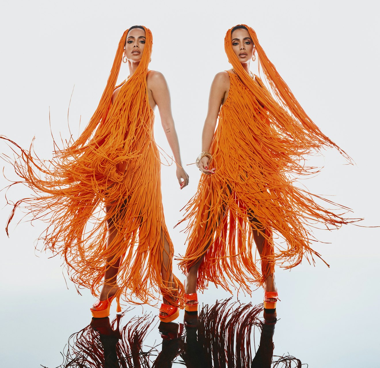 Anitta, Brazillian pop star showing two sides of the same orange outfit, orange dress full of tassel...