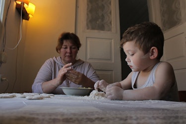 A little boy and his grandma baking at a table, Ukraine.