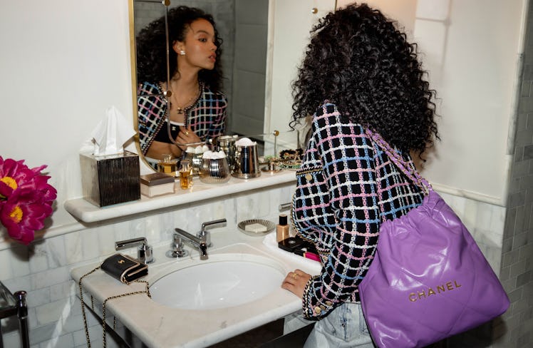 Whitney Peak looking in the mirror with a purple Chanel 22 bag