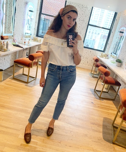 Woman posing in an off-the-shoulder vintage top, mini heels, and denim. 