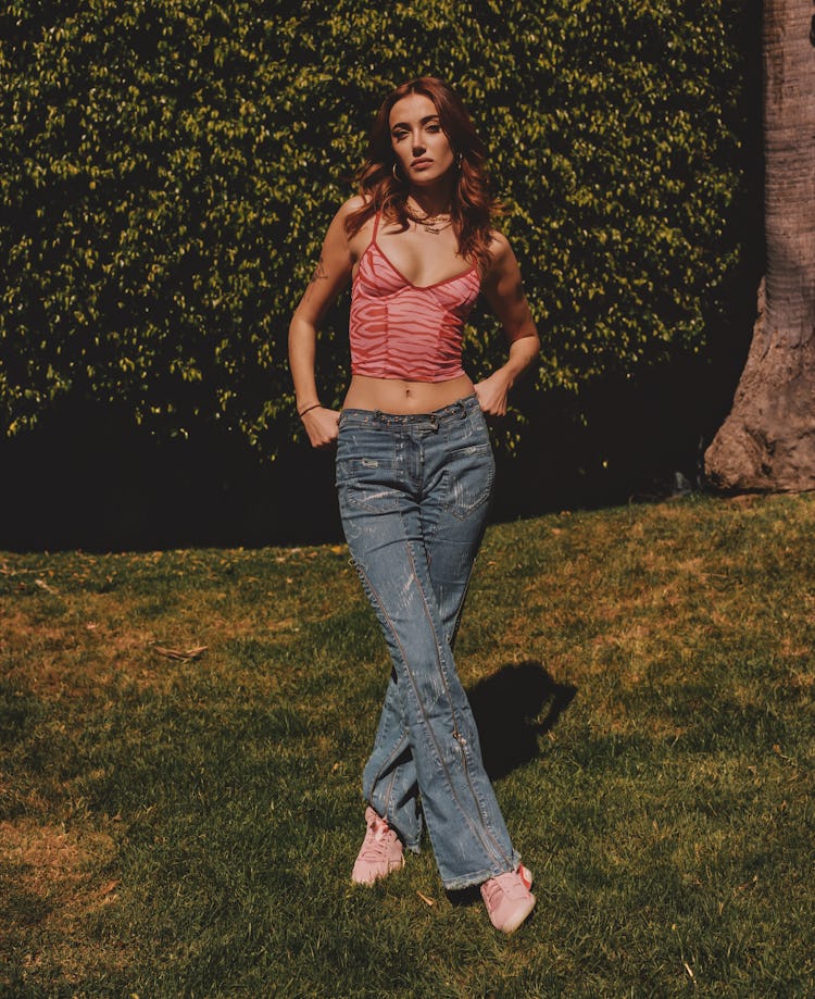 Olivia O'Brien poses in flared denim jeans and a pink zebra-printed top.