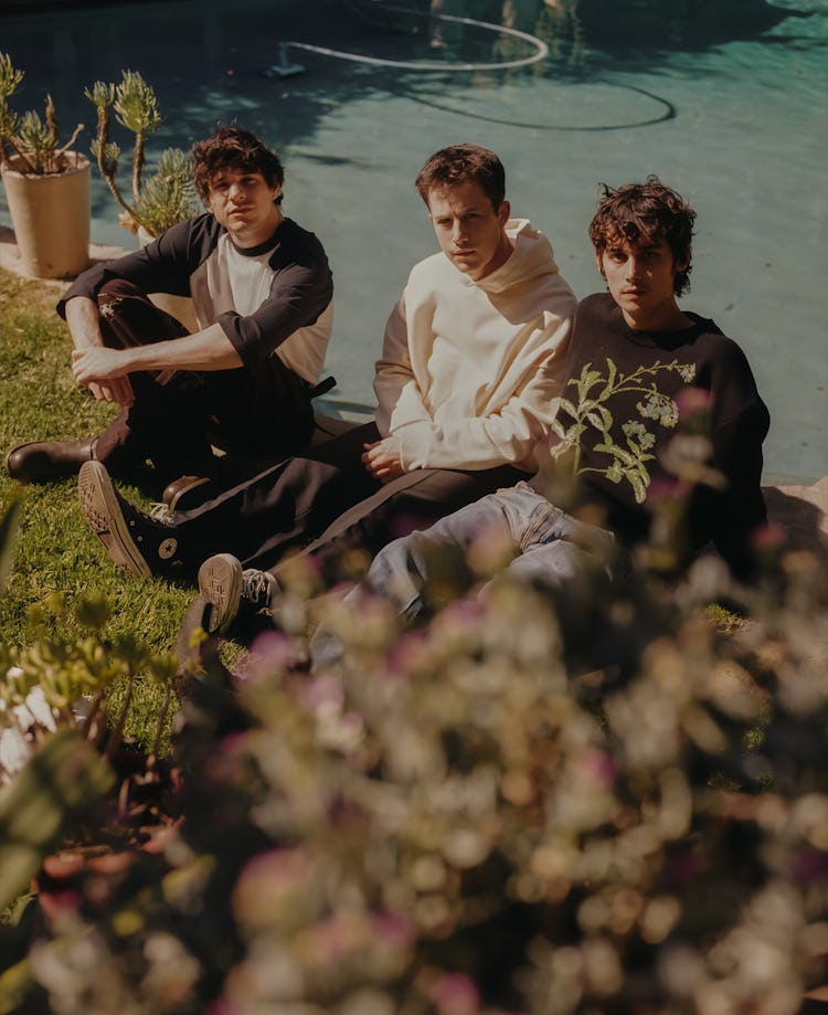 Members of the band Wallows sitting next to the pool 