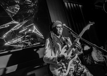 Nile Rodgers playing the guitar behind a microphone