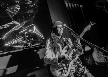 Nile Rodgers playing the guitar behind a microphone