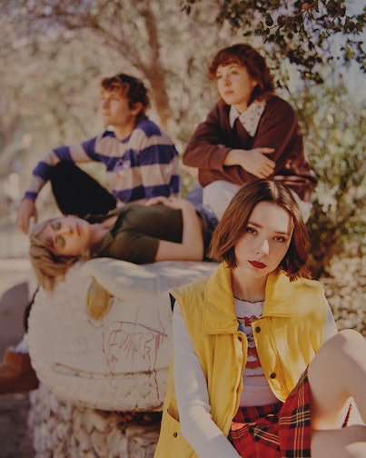 American punk rock band The Regrettes group picture of them sitting in a park surrounded by trees