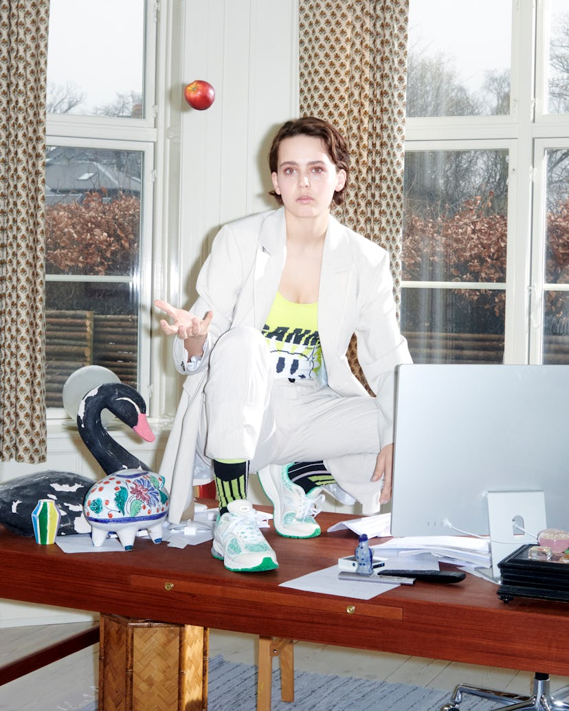 The model standing on a desk in the Ganni and New Balance's Y2K Sneaker.