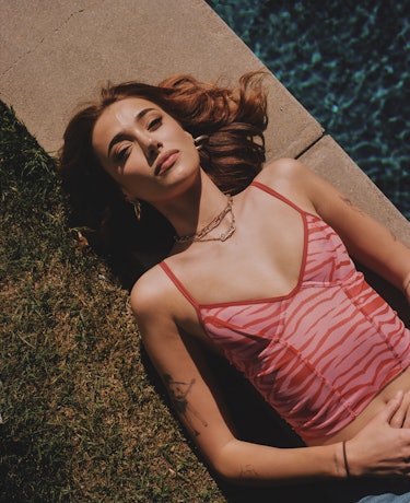 Olivia O'Brien lying next to a pool in a pink zebra-printed top