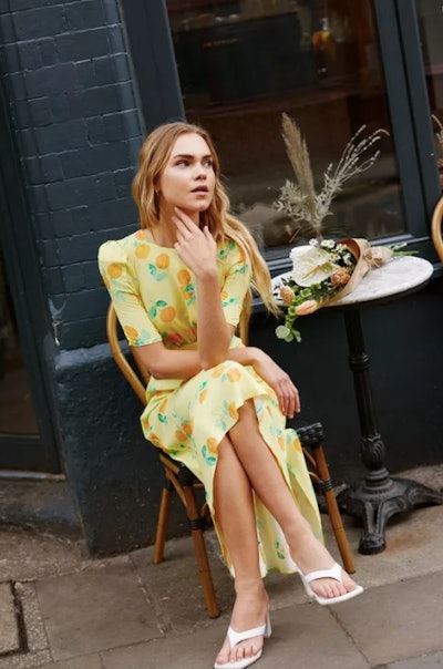 The model wears an orange printed midi slip dress by Nasty Gal that is the perfect wedding guest out...