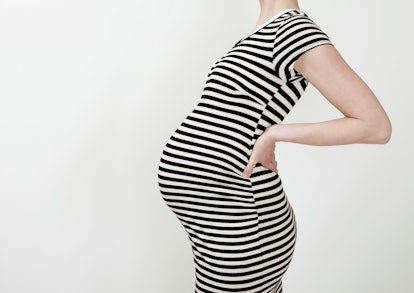 pregnant woman wearing a striped dress; what to know if you're pregnant after a tummy tuck