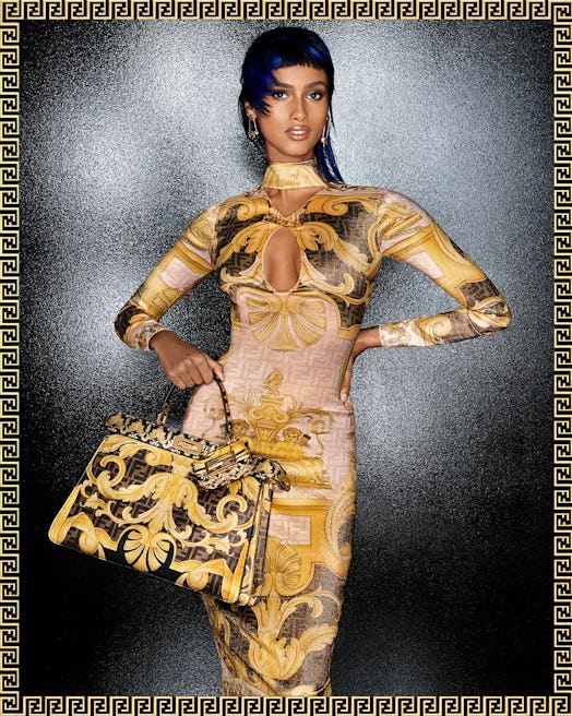 Model in a golden Fendi dress with an opening at the front and a matching large golden Fendi bag. 