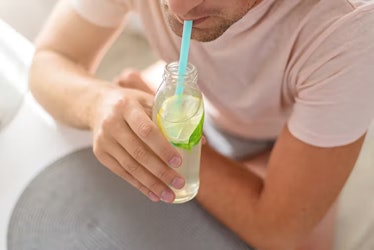 Man drinking bottle of lemon water with mint through a straw