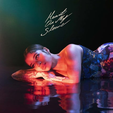 Ella Mai in a floral corset lying on a water surface with her visible reflection in it