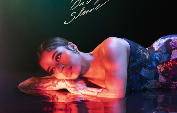 Ella Mai in a floral corset lying on a water surface with her visible reflection in it