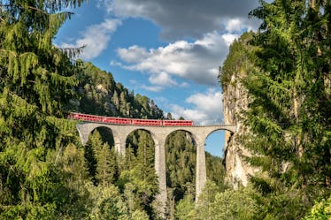 Stunning train trip where the train goes over a bridge overlooking a beautiful natural view.