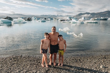 克里斯Burkard和他的两个儿子在岩石海滩,冰川的背景。