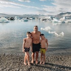 Chris Burkard and his two sons at a rocky beach, with glaciers in the background.