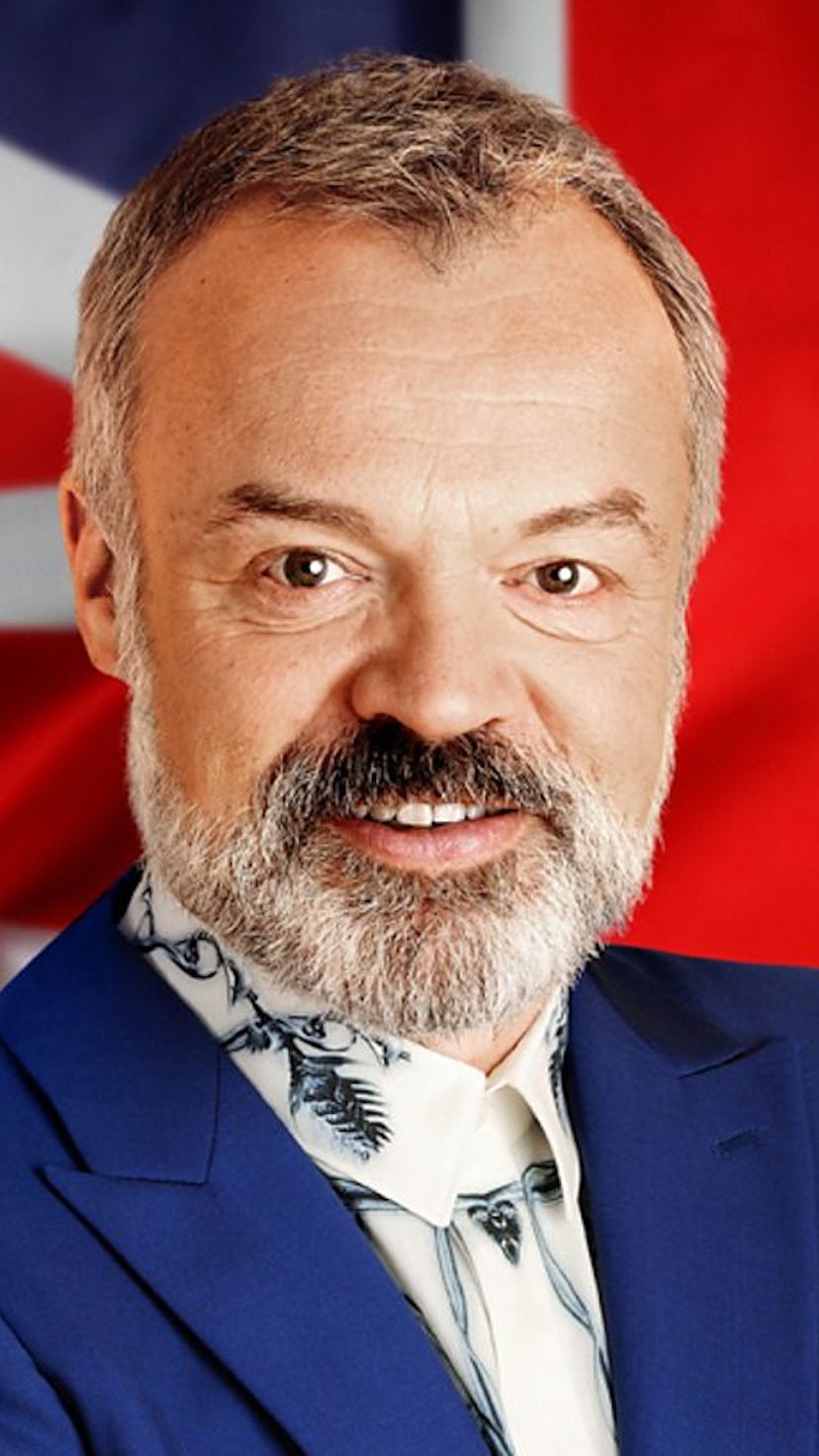 Graham Norton smiling in front of United Kingdom's flag