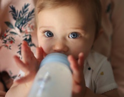 A baby drinking from a bottle, which should not be filled with "homemade baby formula"